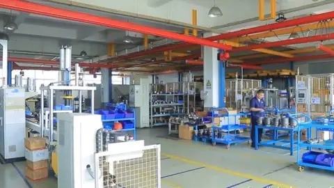 Assembly workshop interior with workbenches, component trolleys and overhead crane rails