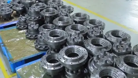 Close-up of stacked final drive housings with bolted flanges on a pallet